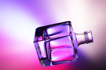 Bottiglietta in vetro trasparente, isolata, in controluce su fondo colorato
