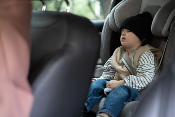 Little girl sleeping on the harness booster seat into a car. Security seat for children.