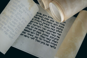 Fototapeta premium Open Megillat Esther (Book of Esther) isolated scroll on black backround. Read on the Jewish holiday of Purim.