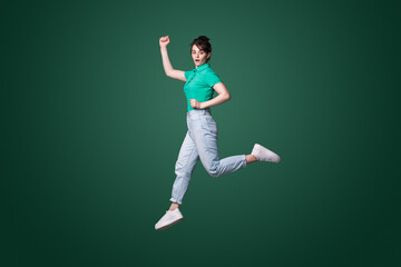 Fototapeta na wymiar Full body profile side photo of young woman jumping with shocked face expression isolated over green background