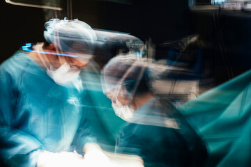 Motion photography with slow exposure of the doctor with mask doing a surgery. Emergency effect.