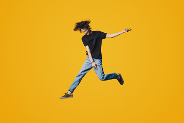 Naklejka na ściany i meble Full length photo of young handsome man jumping high up rejoicing celebrating success isolated yellow color background
