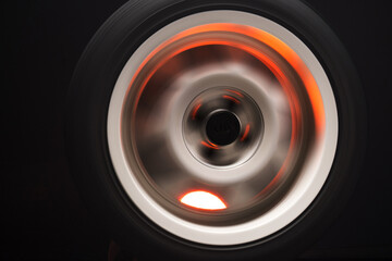 long exposure photography in motion spinning car titanium rims in blurry light	