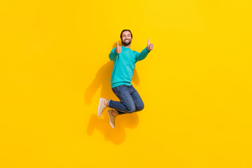Fototapeta na wymiar Full length photo of sweet confident man wear turquoise clothes jumping high thumbs up isolated yellow color background