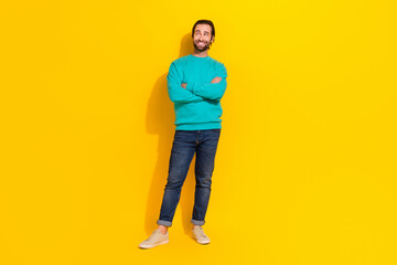 Fototapeta na wymiar Full length photo of dreamy funny man wear turquoise clothes arms crossed looking empty space isolated yellow color background