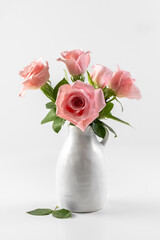 Pink roses in a white ceramic vase on a white background. Card. Copy space. Photo