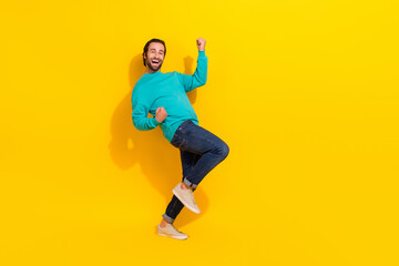 Fototapeta na wymiar Full length photo of excited lucky man wear turquoise clothes rising fists empty space isolated yellow color background