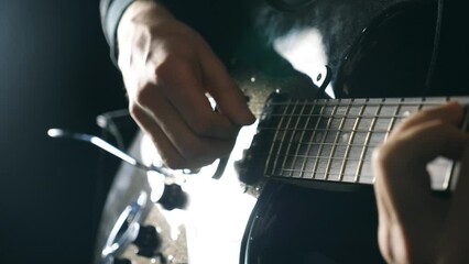 Hands of male musician playing at electric guitar. Mens arms plays solo of rock music. Close up fingers of guitarist at the strings. Beautiful black background at studio. Slow motion Close up