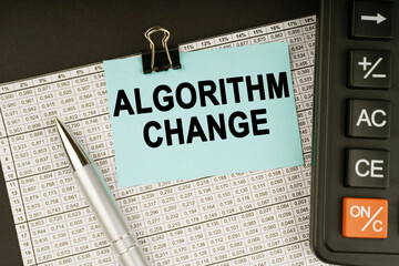 On financial reports lies a calculator, a pen and a sticker with the inscription - Algorithm Change