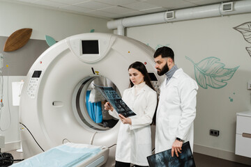 Two doctors discussing x-rays after CT scan of patient abdomen. CT Computed tomography scan...