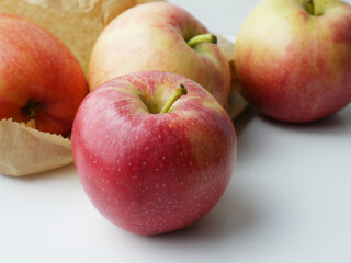 Group of apples on light background and paper bag.