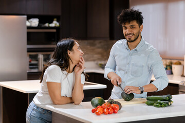 Hispanic couple cooking healthy salad in their kitchen - Young man making healthy recipes together with his partner - Young couple in their kitchen