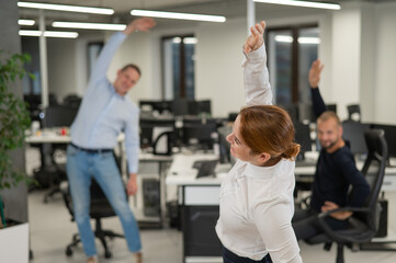 Three office workers warm up during a break. Employees do fitness exercises at the workplace. 
