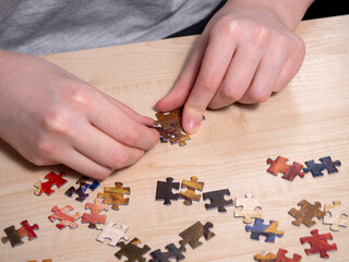 The hands of the man collecting puzzles . The concept of recreation, hobbies, mental health.