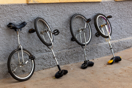 4 unicycles leaning against a wall in a school