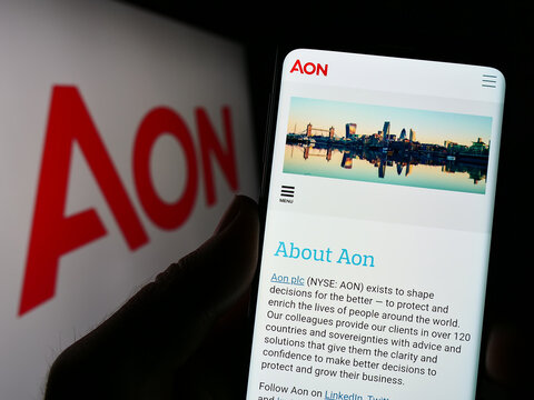 Stuttgart, Germany - 01-27-2023: Person holding smartphone with website of financial services company Aon plc on screen in front of logo. Focus on center of phone display.