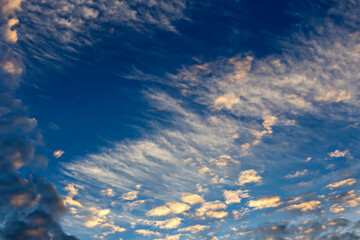 Clouds of different types in the blue sky in the rays of the setting sun