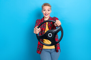 Photo of young funny surprised positive driver student woman first time hold steering wheel enjoy automobile lesson isolated on blue color background