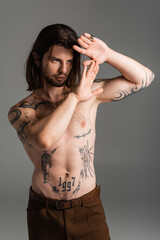 Fototapeta premium Bearded long haired model with tattoo on torso posing isolated on grey.
