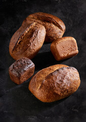 Different types of bread laid out on a dark uniform background
