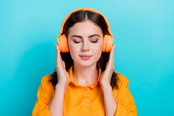 Photo of sweet shiny woman dressed orange shirt closed eyes enjoying music headphones isolated teal color background