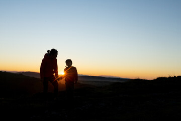 Fototapeta na wymiar Mother and son silhouetted at sunset when walking