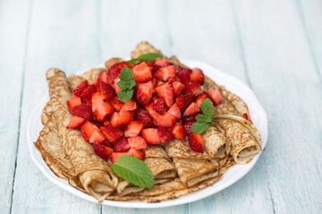 ruddy pancakes with fresh strawberries on a light background