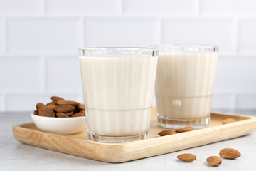 Lactose free almond milk in a glass on a white table and almond kernels. Copy Space. Organic nut milk.