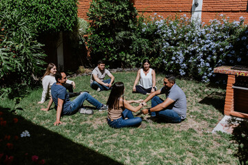 hispanic young couple seated in circle on grass and participating in group therapy session in Mexico Latin America	