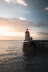 Lighthouse at sunset vertical photo wallpaper. Fécamp's red lighthouse in front of the sea in Normandy, France. Symbol of hope - obrazy, fototapety, plakaty