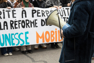 personne avec un mégaphone devant une banderole d'une manifestation lors de grèves en france...