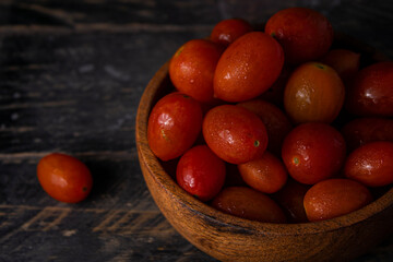 Tomates rojos en cuenco de madera sobre mesa de madera 