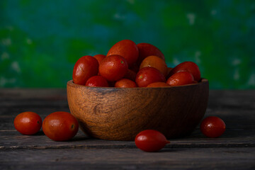 Tomates rojos en cuenco de madera sobre mesa de madera y fondo verde