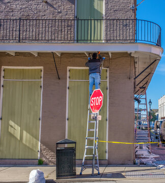 Unidentified Man on a Ladder Applying a Weather Sealant to the Underside of a Balcony in the French Quarter of New Orleans, Louisiana, USA