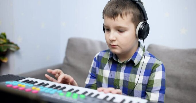 Boy playing synthesizer at home. Kid practicing piano lesson
