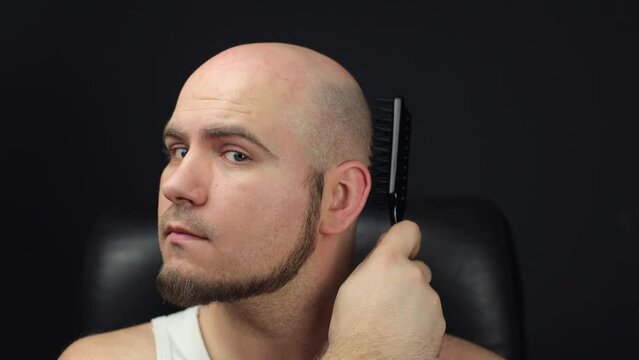 The bald man takes a comb and combs his head. Combing his bald head, A man without hair