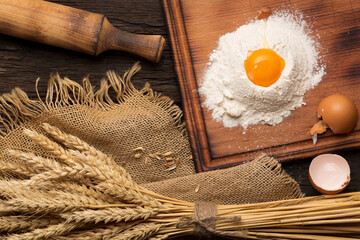 Fototapeta na wymiar Ingredients for baking bread and bread ears on a wooden vintage background, rustic style