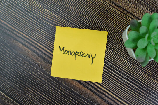 Concept of Monopsony write on sticky notes isolated on Wooden Table.