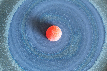 A sugary gummy candy on a flat blue spiral textured background