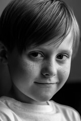 Portrait redhead freckled boy, close-up. Smiling little child. Expressive facial emotions. Selective focus. Black and white photography. High quality photo