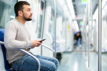 Portrait of european man standing in underground carriage and using his phone