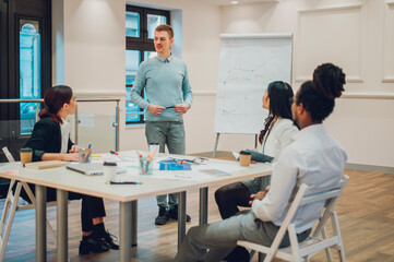 Fototapeta premium Redhead businessman holding a meeting to his diverse colleagues in an office