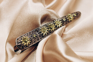 Vintage bronze hair clip with sapphires on a silk background.