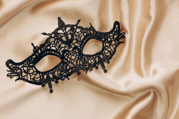 Sexy black lace stylish masquerade mask on golden silk sheet.