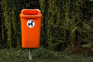 Fototapeta na wymiar orange trash can basket, Dispose dog waste in a trash can. Responsibility for people around the environment.
