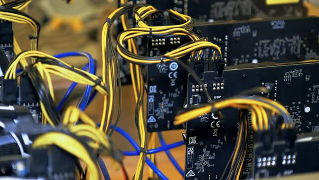Cryptocurrency mining equipment on a large farm. Close-up of electronic devices with fans, many video cards on the motherboard, cryptocurrency miners. The concept of passive income