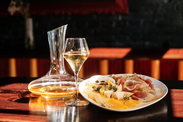 decanter and a glass of white wine. cheese set with  jam, fruit and nuts