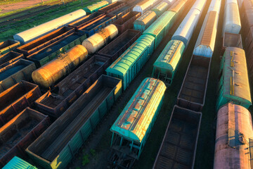 Drone view of freight trains at sunset. Railway cargo wagons with goods on railroad. Aerial view of...