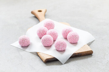 Light airy strawberry cream dessert spherical shape, sprinkled with coconut chips. On a serving board. Light grey background
