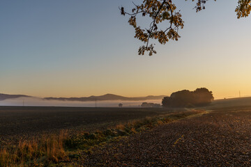 Beautiful sunrise over the mountains in the area of still shaded farmland